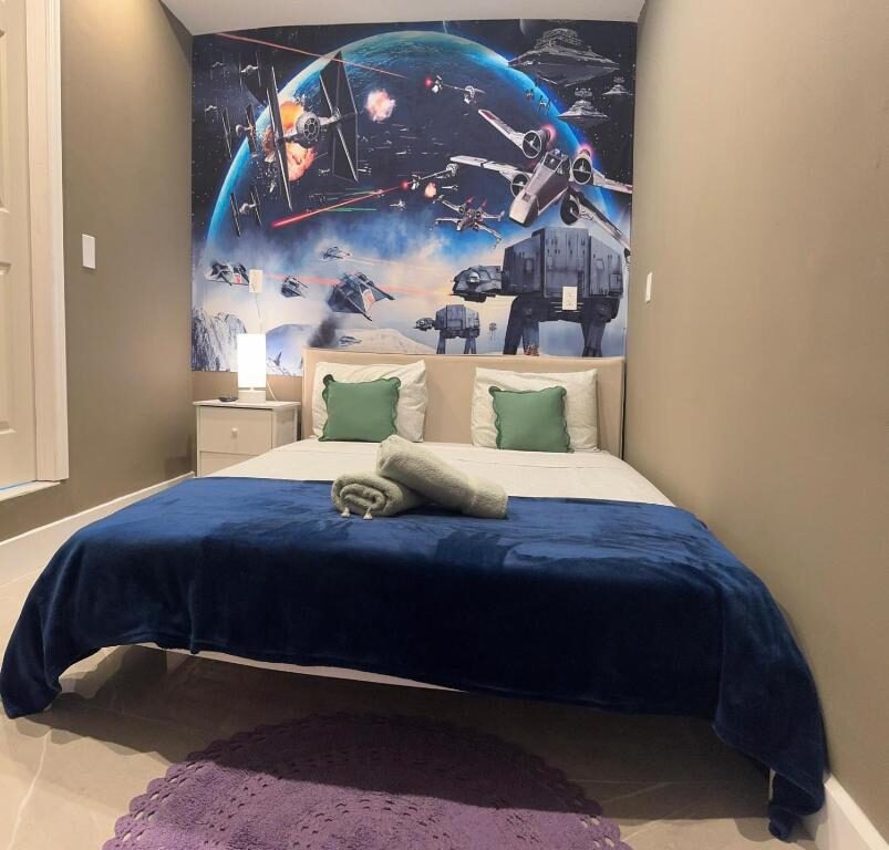 Double bed with a large Star Wars space battle mural behind it