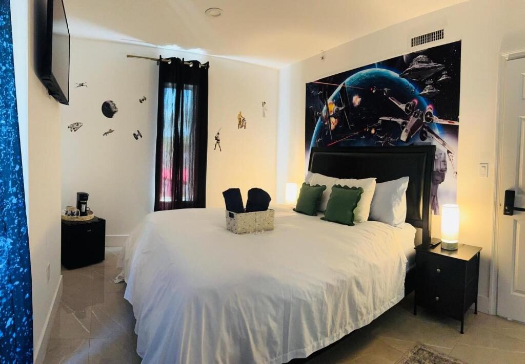 Bright room with white bedding, nightstands and a Star Wars mural